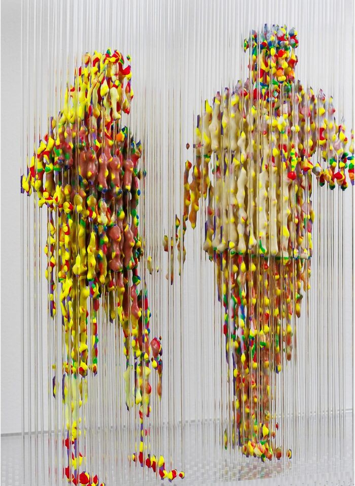 Three-dimensional paintings of people by Chris Dorosz, using colorful suspended beads to create fragmented human figures.