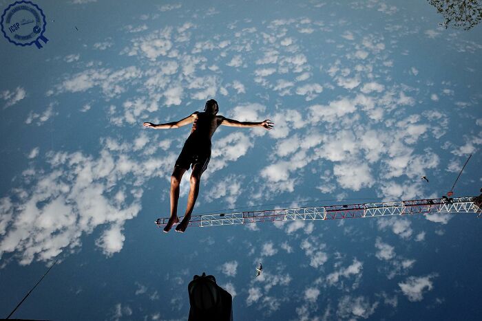 A person appears to dive into a sky reflection, showcasing Gökhan Arer’s unique street photography perspective.