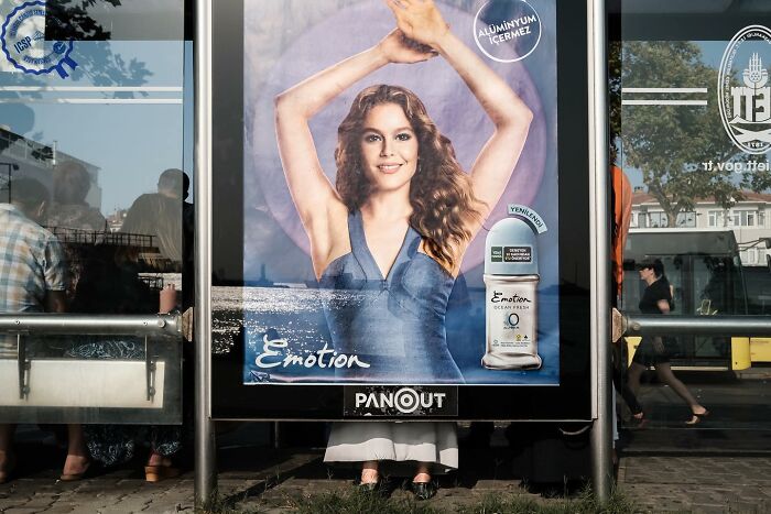Perfectly timed photo of a bus stop ad creates an illusion with a woman's arms matching a pedestrian's legs below.