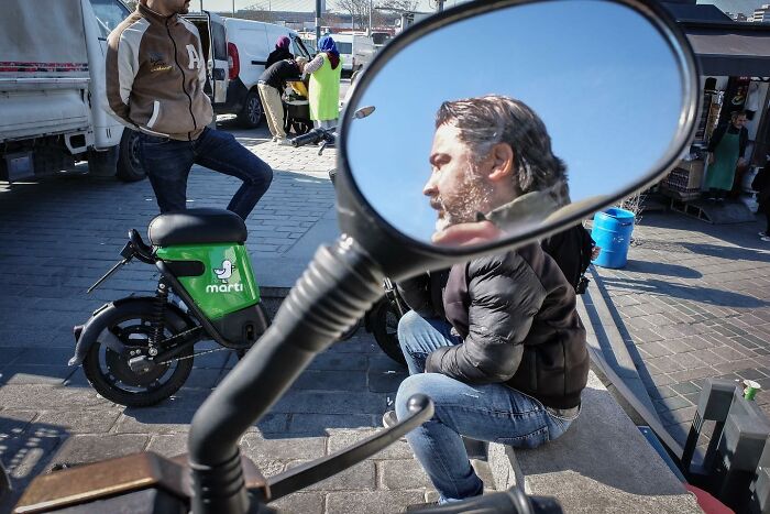 Street scene reflecting in a motorcycle mirror, capturing a candid moment that shows the street differently.