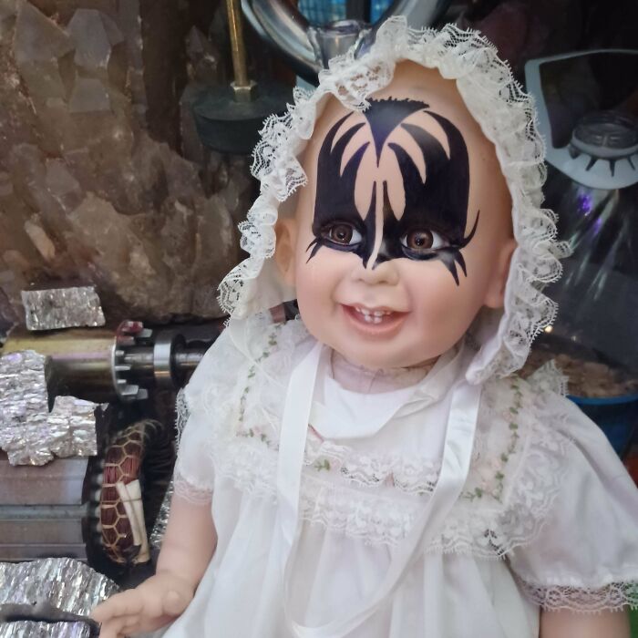 Doll in a white lace dress with black face paint resembling a redneck engineer's quirky creation.