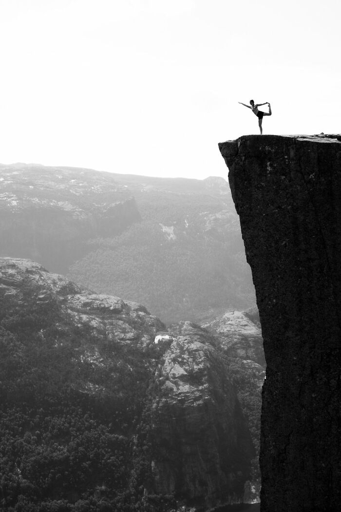 Ballet dancer posing on a cliff edge, capturing the essence of Oslo with dramatic landscapes in the background.