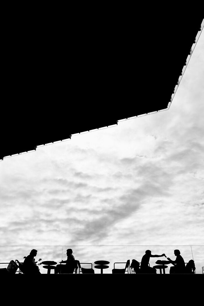 Silhouette of people at an outdoor café, capturing the essence of Oslo's streets under a dramatic sky.