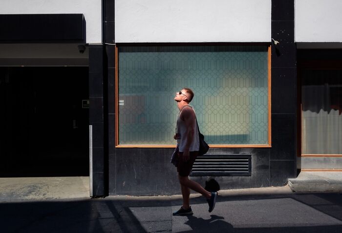 A man strolling under sunlight on a street in Stockholm.