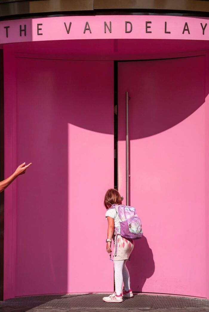 Girl with a purple backpack approaches a pink entrance titled "The Vandelay" in Oslo.
