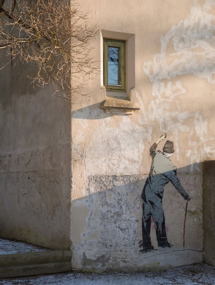 Street art on a wall in Oslo, depicting a person painting clouds, capturing the essence of the city's urban scene.
