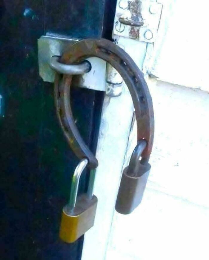 Improvised lock using a horseshoe secured by two padlocks on a door latch, showcasing redneck engineering creativity.