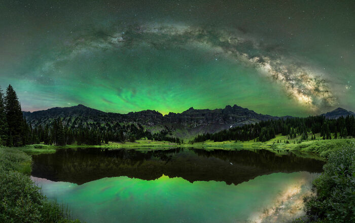 Stunning night sky over a serene lake in a nature competition-winning photo, showcasing vibrant green and starry skies.