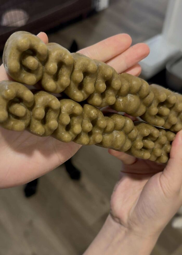 Hands holding DIY project of textured, spiral-shaped crafts on a wooden floor background.