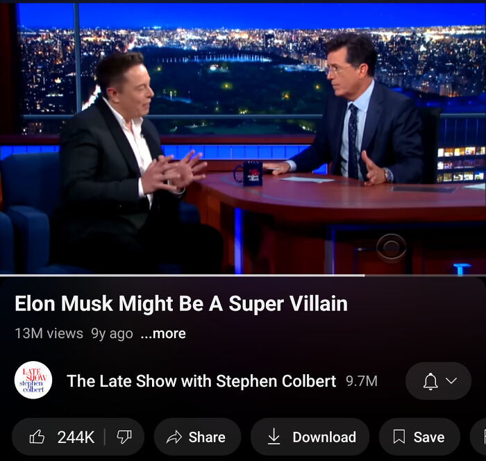 Elon Musk interviewed by Stephen Colbert on a late-night show discussing predictions and accuracy in a studio setting.