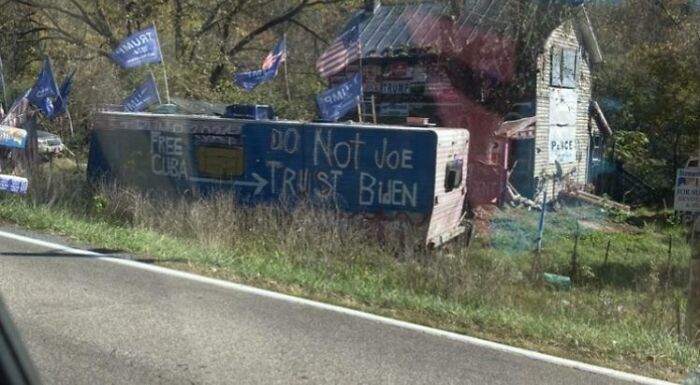 Sign fail on RV reads “Do Not Joe Trust Biden” with flags and a house in the background.