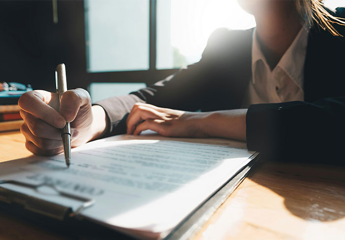 Person signing a document in a well-lit office, symbolizing the end of a marriage. Person signing a document in a well-lit office, symbolizing the end of a marriage.