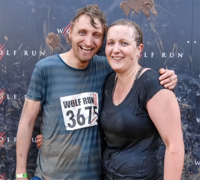 Participants at Wolf Run event, muddy and smiling, against dark backdrop. Participants at Wolf Run event, muddy and smiling, against dark backdrop.