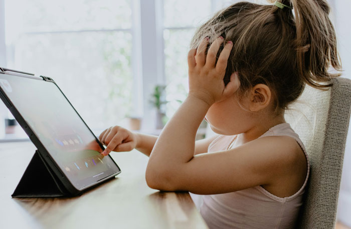 Child with frustrated expression using a tablet, illustrating a technique to raise entitlement-free kids. Child with frustrated expression using a tablet, illustrating a technique to raise entitlement-free kids.