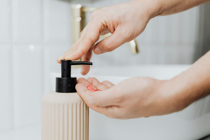 Hands using soap dispenser, illustrating common hygiene habits.