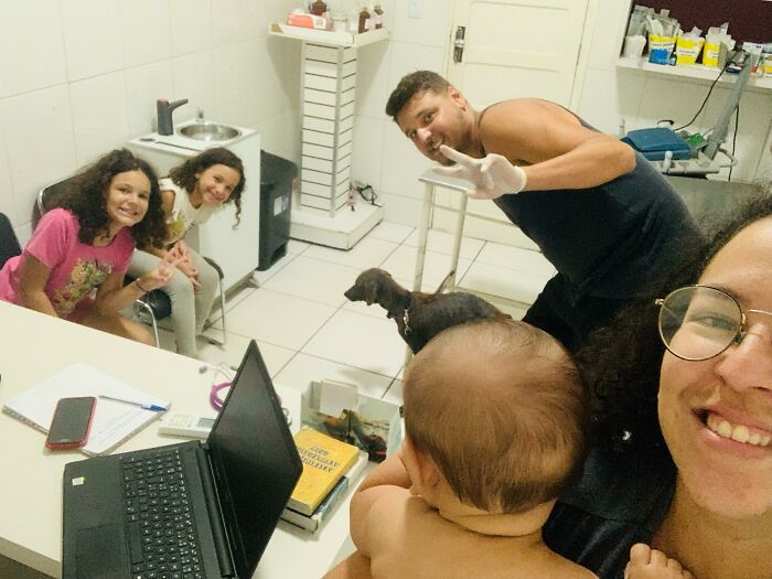 Family with a stray dog in a cozy room; two children smiling, an adult holding a baby, and one man posing cheerfully. Family with a stray dog in a cozy room; two children smiling, an adult holding a baby, and one man posing cheerfully.