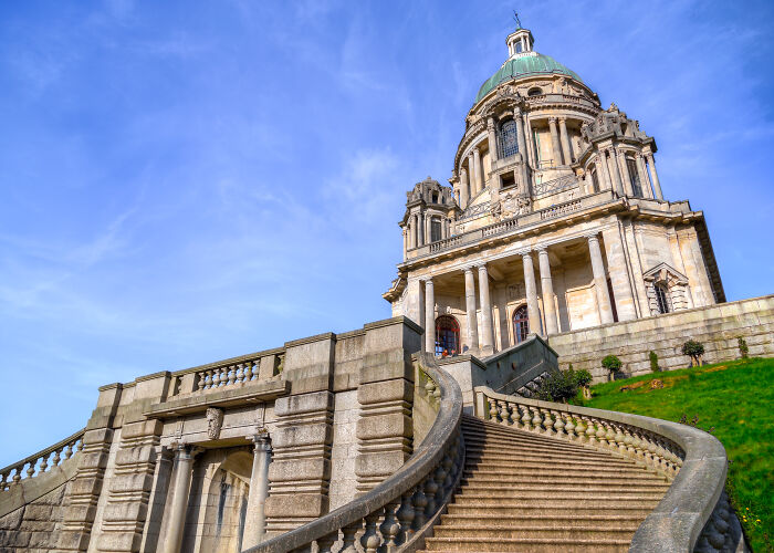 Large historic stone structure with grand staircase under a blue sky, showcasing beautiful but potentially useless architecture.