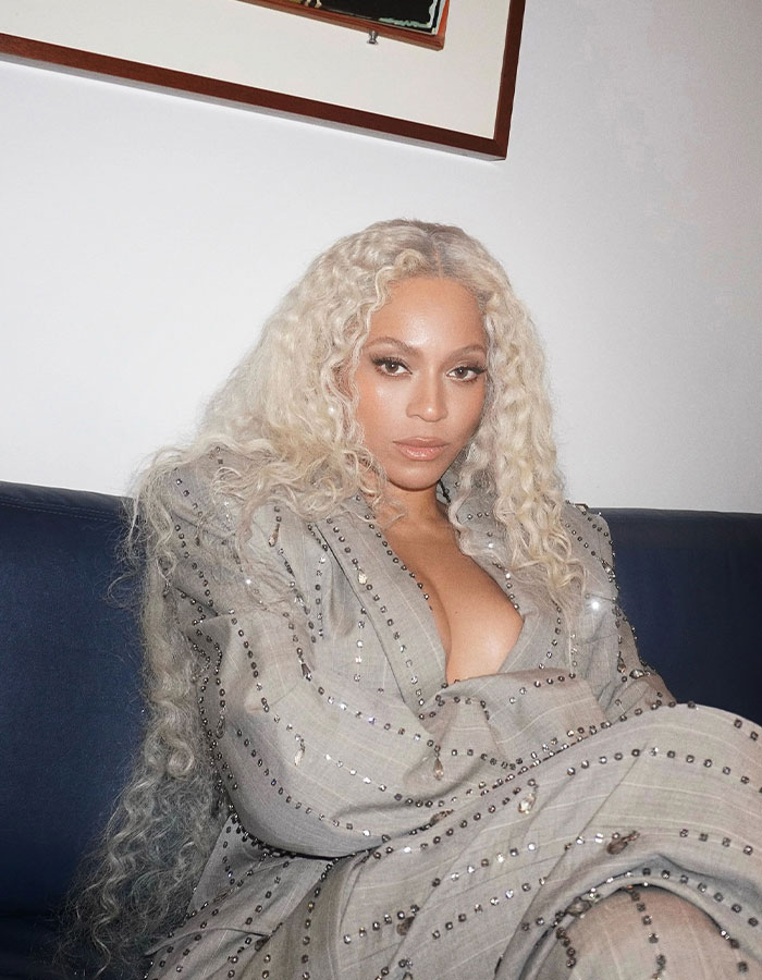 Woman with blonde hair in a studded beige outfit, sitting on a couch, related to a skin tone debate at the Grammys. Woman with blonde hair in a studded beige outfit, sitting on a couch, related to a skin tone debate at the Grammys.