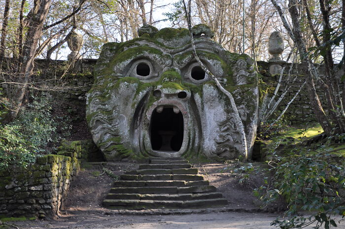 A beautiful, whimsical stone structure shaped like a face with an open mouth, surrounded by trees.