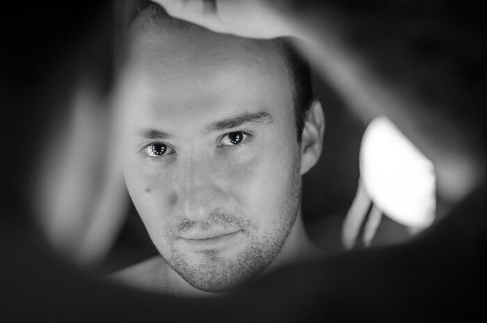 A person staring into a mirror, capturing reflections in a dimly lit room, relating to common superstitions.