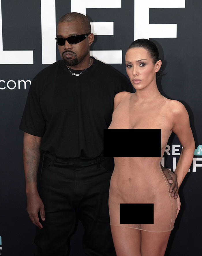 Bianca Censori and Kanye West standing together, posing at a public event. Bianca Censori and Kanye West standing together, posing at a public event.