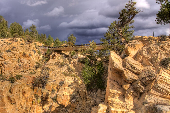 Scenic view of a bridge on a legendary American road route with rocky cliffs and dramatic skies.