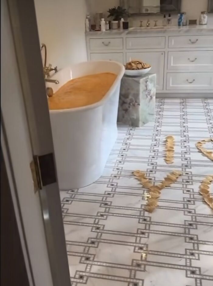 Bathtub filled with orange water, cookies on a pedestal, and "I Love You" spelled with objects on the floor. Bathtub filled with orange water, cookies on a pedestal, and "I Love You" spelled with objects on the floor.