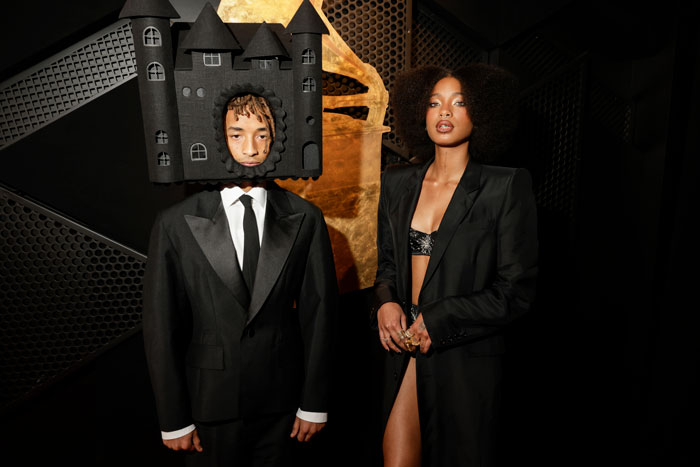 Young man in a castle-themed outfit and woman in a black suit at the Grammys 2025. Young man in a castle-themed outfit and woman in a black suit at the Grammys 2025.