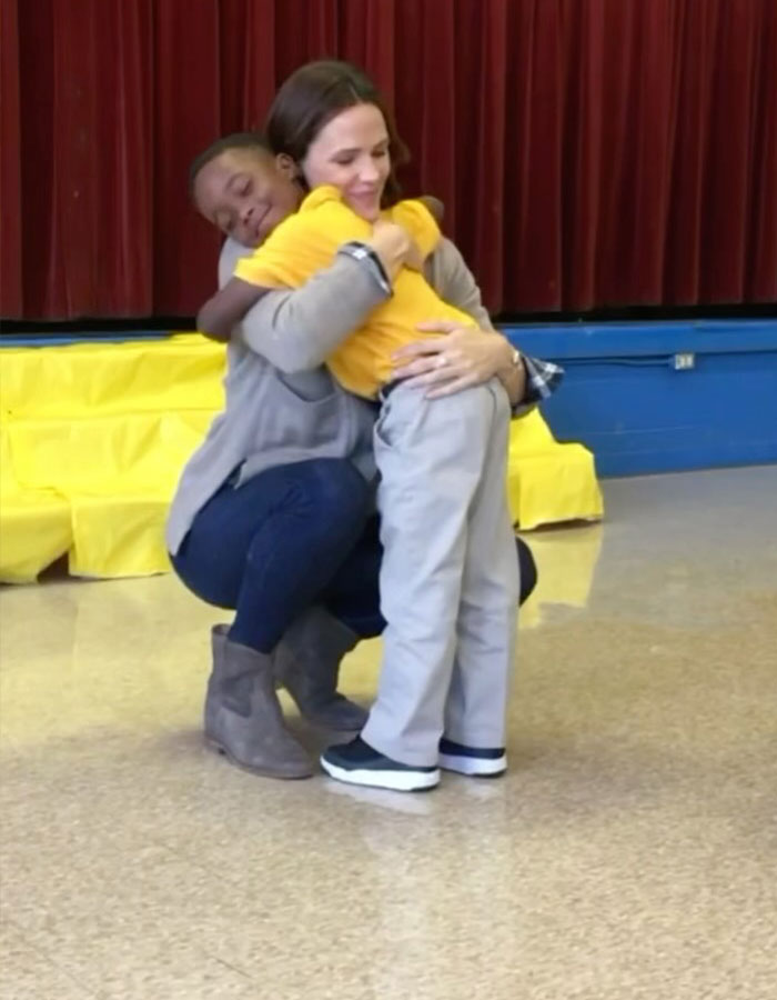 A woman hugging a child in a school setting, both smiling warmly, highlighting a positive emotional moment. A woman hugging a child in a school setting, both smiling warmly, highlighting a positive emotional moment.