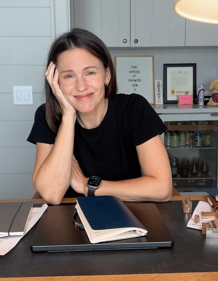 Woman in a black shirt smiling at a desk with notebooks and a laptop. Woman in a black shirt smiling at a desk with notebooks and a laptop.