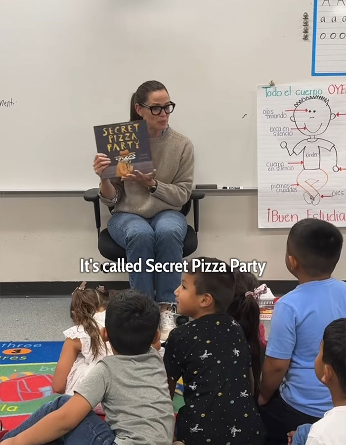 Woman reading "Secret Pizza Party" to children in a classroom setting. Woman reading "Secret Pizza Party" to children in a classroom setting.