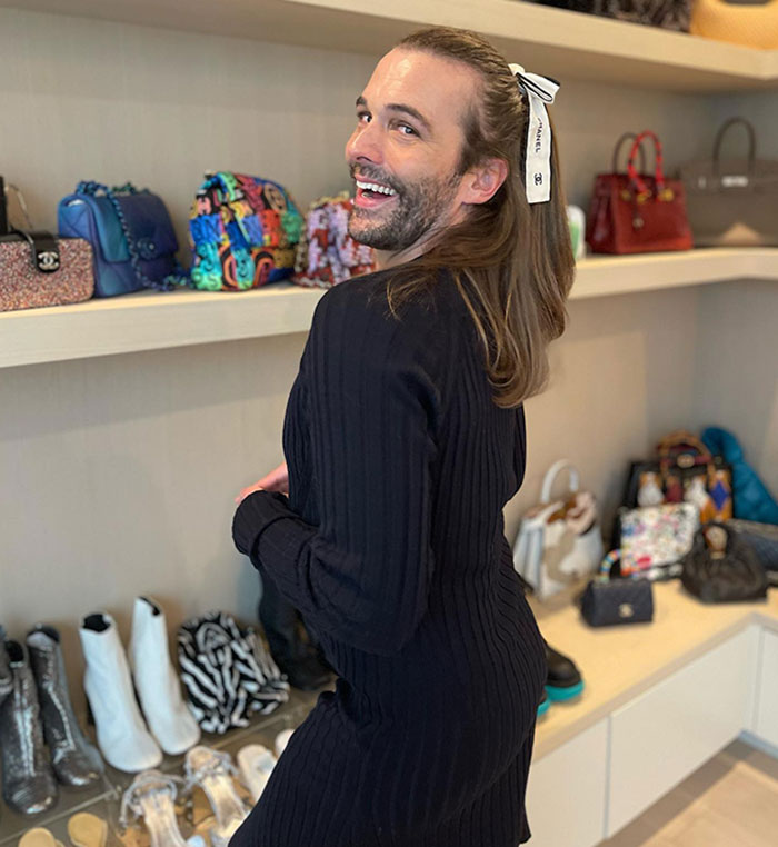 Jonathan Van Ness smiling, showcasing weight loss in a black outfit, standing in front of a shelf with colorful bags and shoes. Jonathan Van Ness smiling, showcasing weight loss in a black outfit, standing in front of a shelf with colorful bags and shoes.