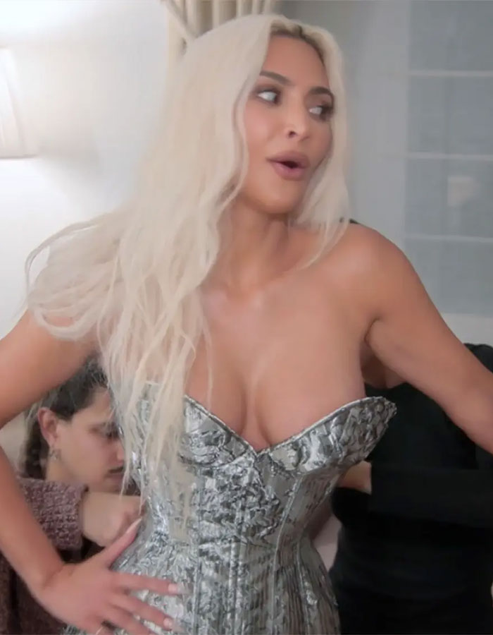 Woman in a silver corset, styled with long blonde hair. Woman in a silver corset, styled with long blonde hair.