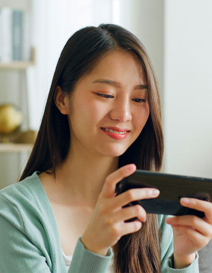 Woman using mobile game with period tracker feature, wearing a green cardigan, sitting indoors. Woman using mobile game with period tracker feature, wearing a green cardigan, sitting indoors.