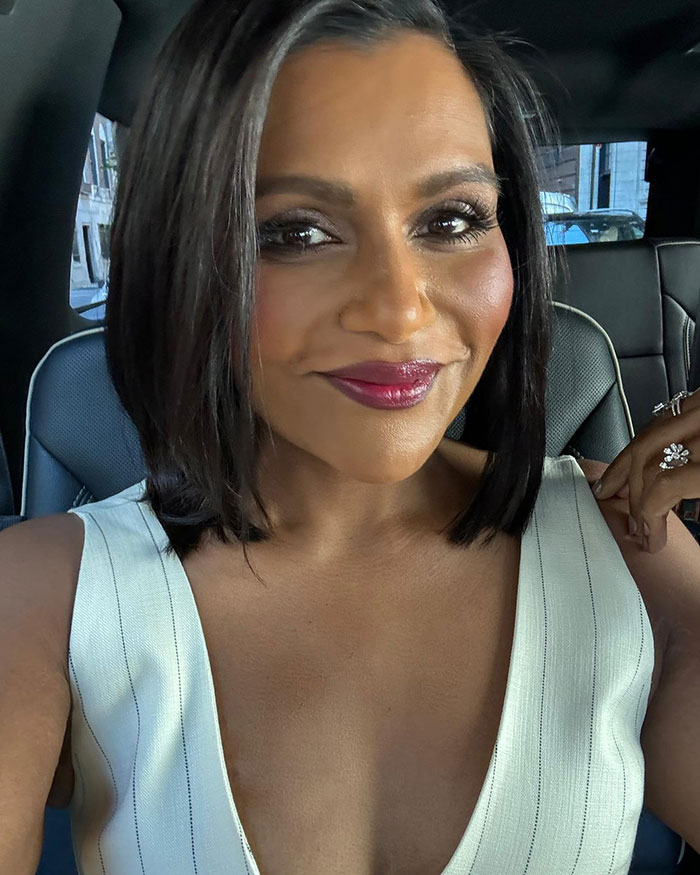 Mindy Kaling showcasing slim figure at a movie premiere, wearing a white dress and smiling in a car. Mindy Kaling showcasing slim figure at a movie premiere, wearing a white dress and smiling in a car.