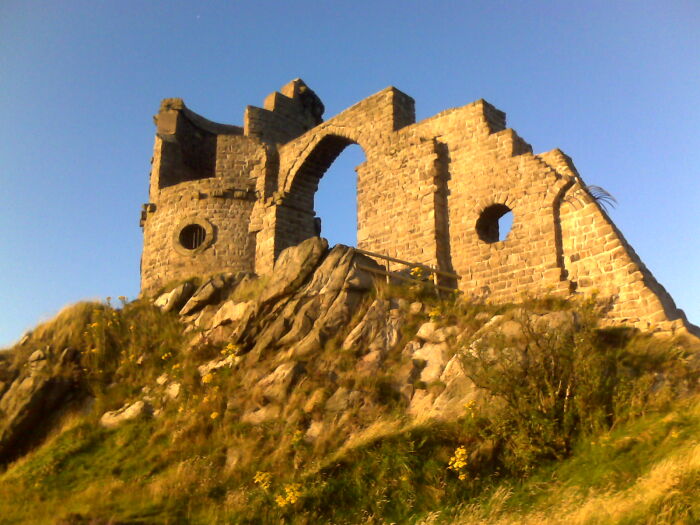 Stone ruins on a hill under a clear blue sky, illustrating beautiful useless buildings.