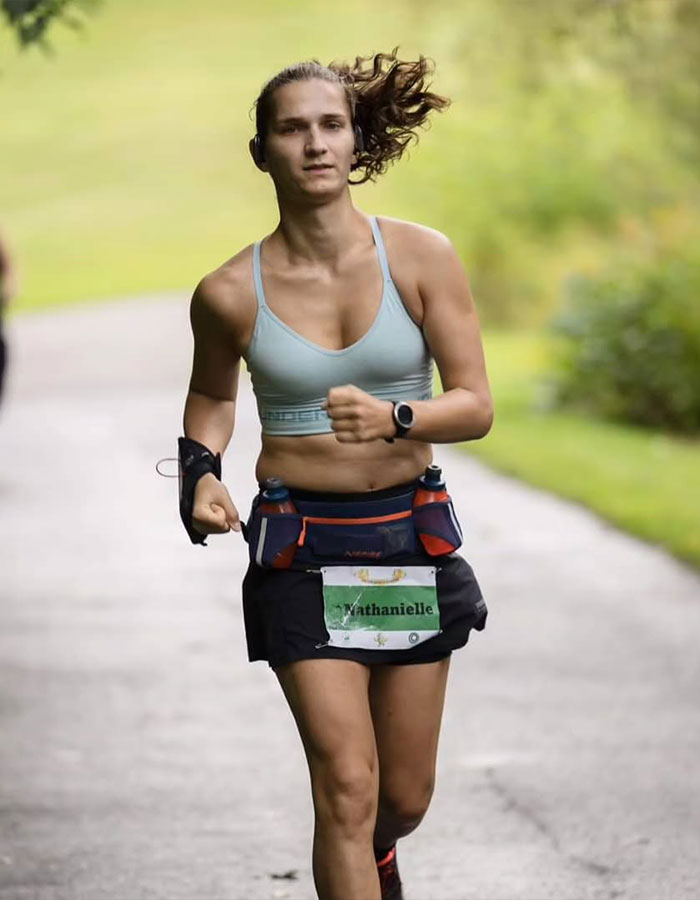 Trans runner competing in a race, advocating for transgender inclusion in women's sports, running on a park trail. Trans runner competing in a race, advocating for transgender inclusion in women's sports, running on a park trail.