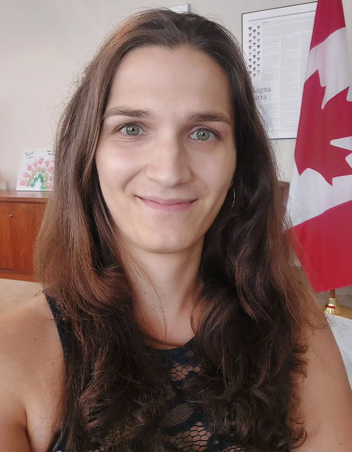 Person advocating for transgender inclusion in sports, standing in front of Canadian flag, in an indoor setting. Person advocating for transgender inclusion in sports, standing in front of Canadian flag, in an indoor setting.