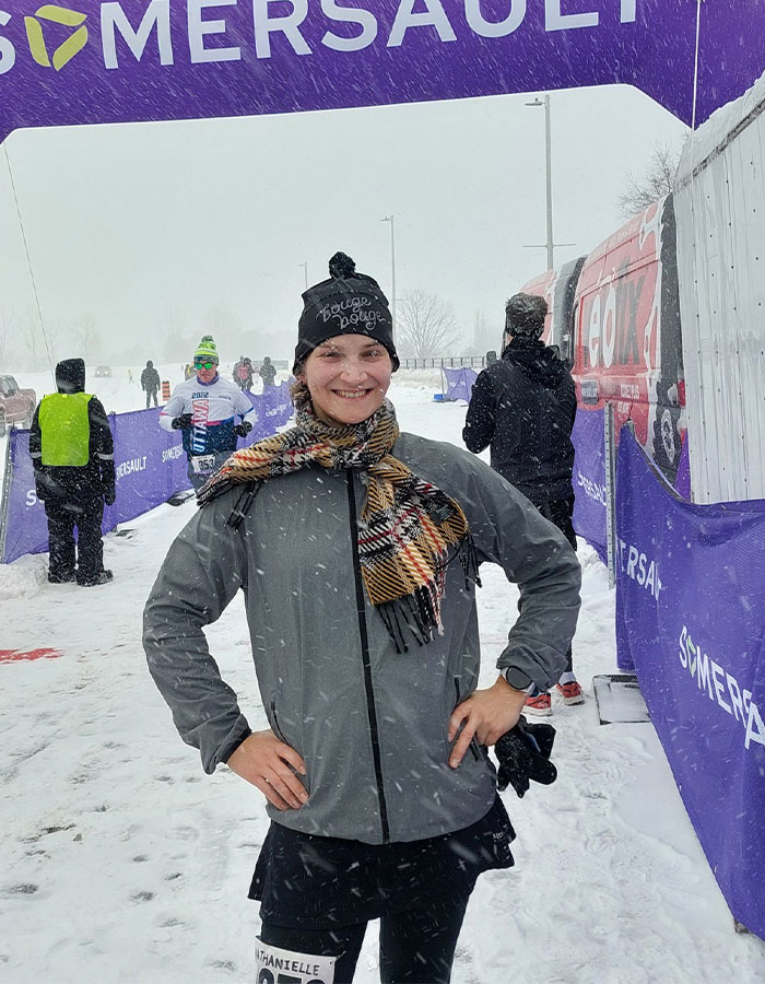 Trans runner standing confidently in snowy race finish area, promoting inclusion in women's sports. Trans runner standing confidently in snowy race finish area, promoting inclusion in women's sports.