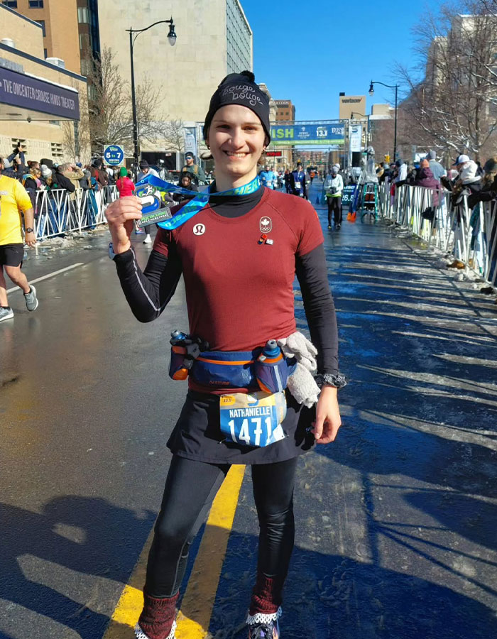 Runner holding a medal, wearing a race bib, advocating for transgender inclusion in women's sports at the finish line. Runner holding a medal, wearing a race bib, advocating for transgender inclusion in women's sports at the finish line.