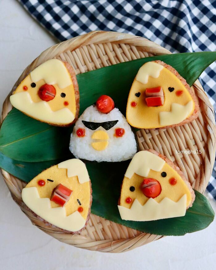 Creative lunchbox art with cute rice ball and egg designs by a Japanese artist.