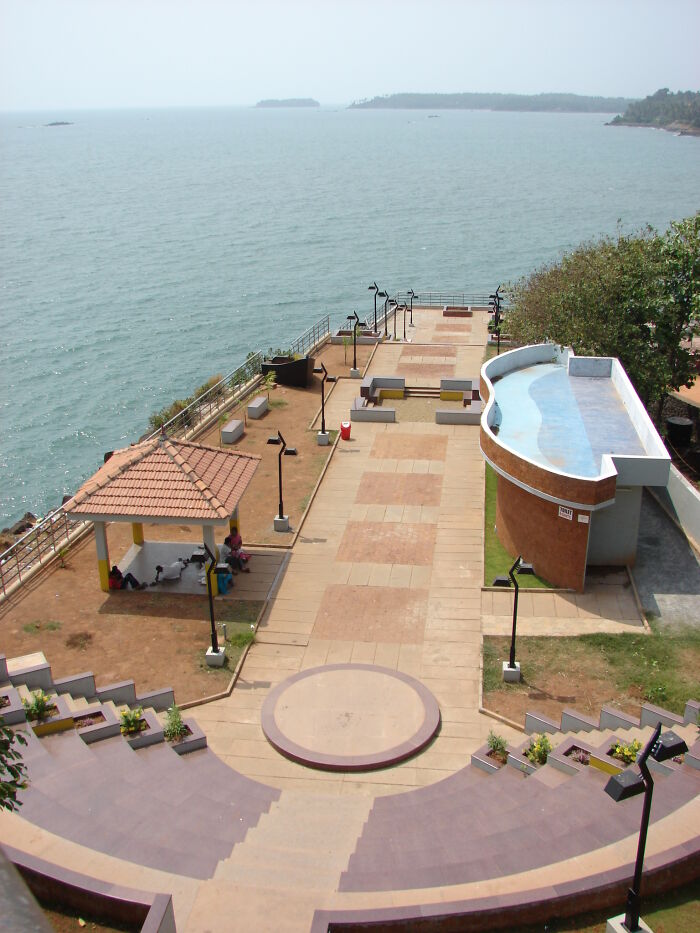Elevated view of a beautiful but useless building near the sea with an empty promenade and circular amphitheater steps.
