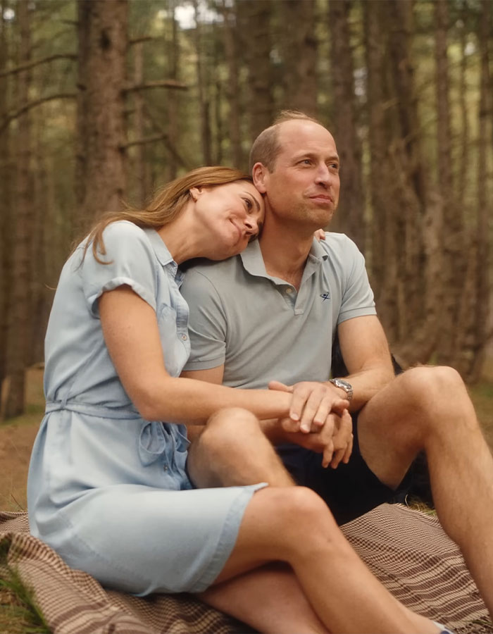 Two people sitting on a picnic blanket in the woods, one resting their head on the other's shoulder. Two people sitting on a picnic blanket in the woods, one resting their head on the other's shoulder.