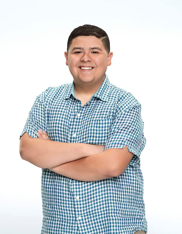 Modern Family star in plaid shirt, smiling with arms crossed against a white background. Modern Family star in plaid shirt, smiling with arms crossed against a white background.