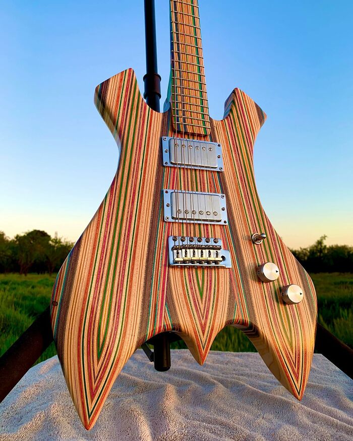 Stunning guitar crafted from colorful, striped materials, showcasing unique design against a clear sky backdrop.