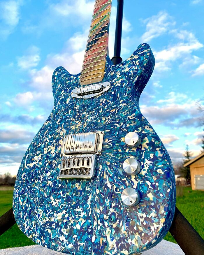 Stunning guitar crafted from unexpected materials, featuring a vibrant blue and white speckled design against a clear sky.