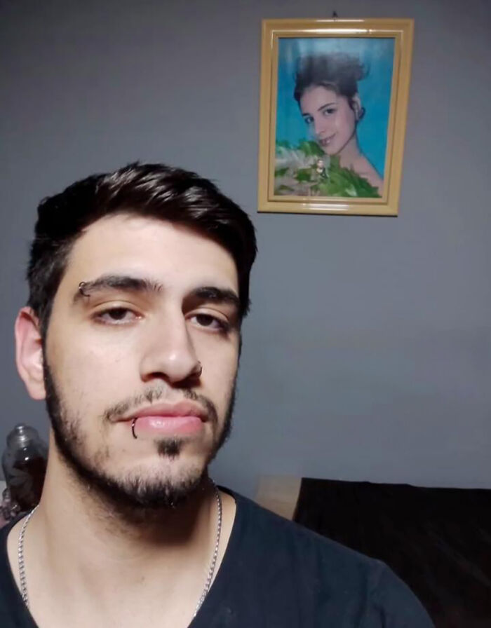 "Man stands in front of a portrait, setting up a family prank for online laughter. "Man stands in front of a portrait, setting up a family prank for online laughter.