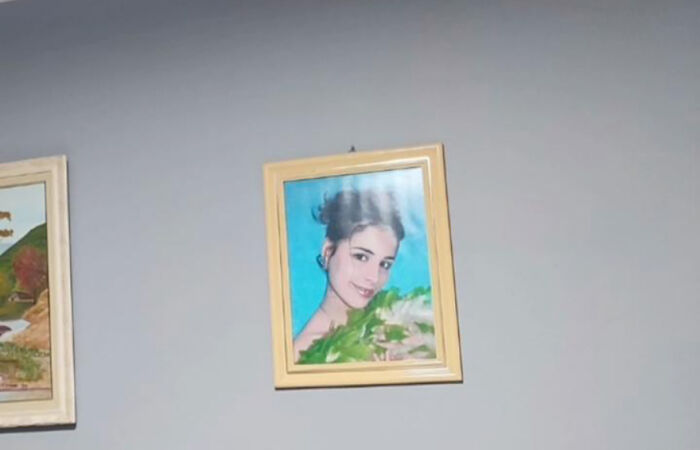 A family prank with a funny portrait of a smiling person in a wooden frame on a plain wall. A family prank with a funny portrait of a smiling person in a wooden frame on a plain wall.