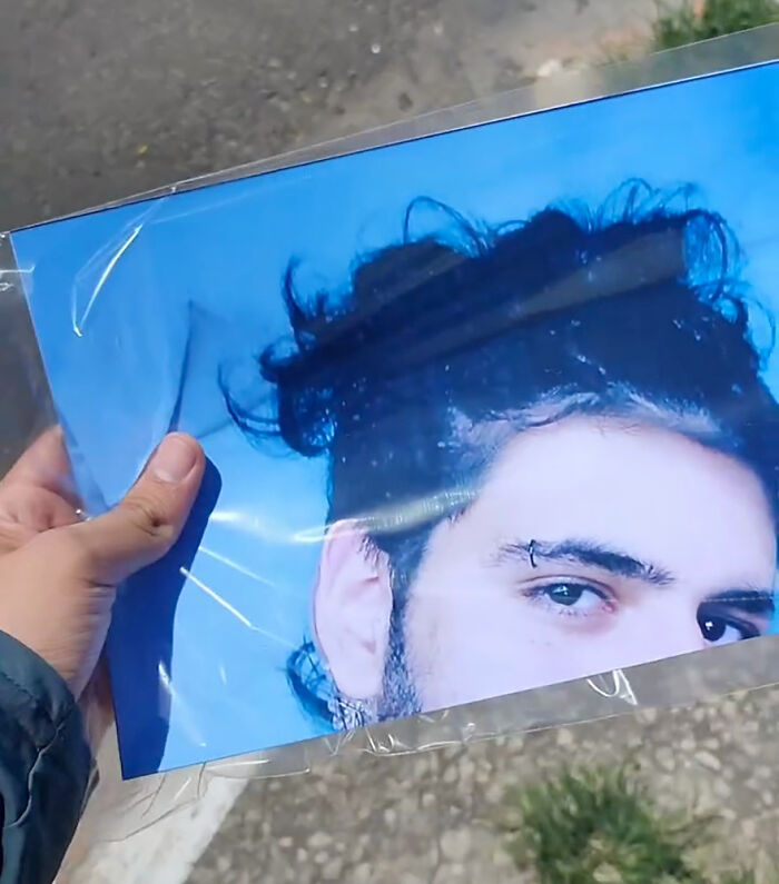 A person holding a printed photo close-up as part of a funny prank on their family. A person holding a printed photo close-up as part of a funny prank on their family.