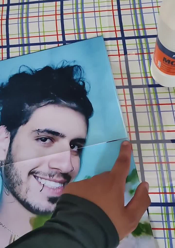 A person pointing at a cutout photo on a colorful grid tablecloth, part of a funny prank on family. A person pointing at a cutout photo on a colorful grid tablecloth, part of a funny prank on family.